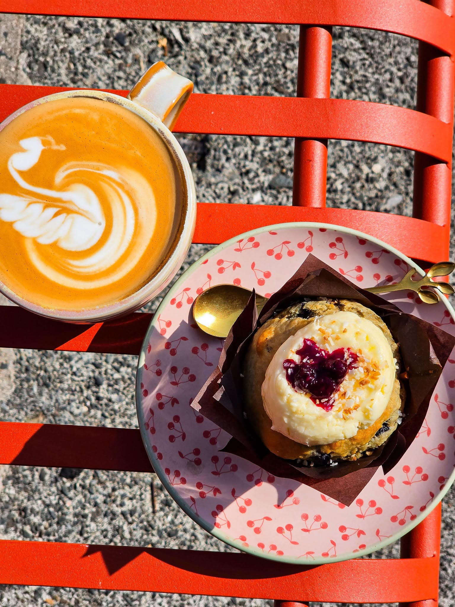 Flat white and a glazed bun on an outdoor table